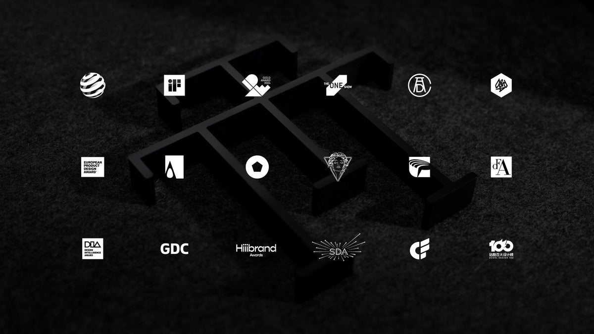Design award logos displayed over a black TT monogram sculpture